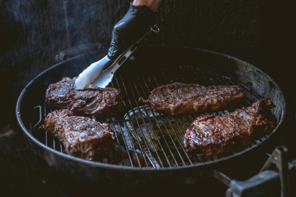 pexels-photo-8477355-8477355 Juicy steaks being grilled over charcoal, perfect for a delicious BBQ meal.